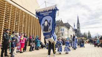 Festively dressed Törmleguger Vaduz at the carnival parade in Vaduz, Liechtenstein, in front of the government building and cathedral.