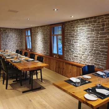 Stylish dining room with long wooden tables, stone walls and modern decoration