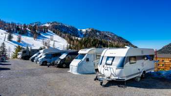 Several motorhomes are parked on the sunny pitch in Malbun with a mountain panorama in the background