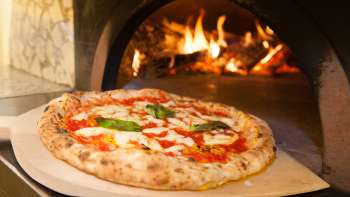 Close-up of a pizza in front of a pizza oven at Ristorante Pizzeria Sapori