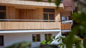 Exterior view of the guest house at Camping Mittagsspitze with wooden façade and balcony in a natural setting. Exterior view of the guest house at Camping Mittagsspitze with wooden façade and balcony in a natural setting.