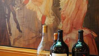 Three bottles of wine in front of an artistic mural in the Brasserie Burg