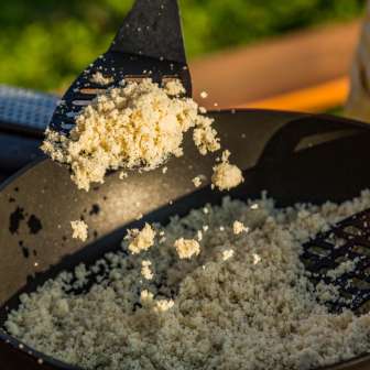 Preparation of Rebel, a traditional semolina dish from Liechtenstein, with spatulas over an open pan