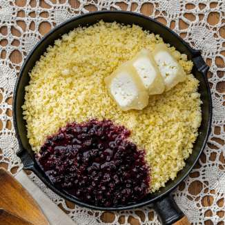 Rebel (Ribe) in a pan with melted butter and cranberries, served on a crocheted tablecloth - typical Liechtenstein dish