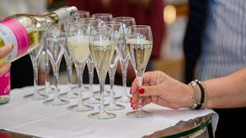 Several champagne glasses are filled on a white cloth