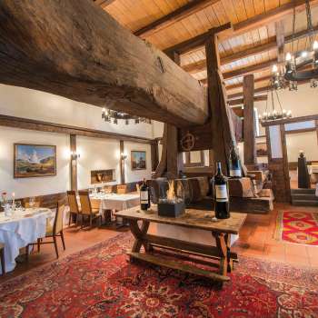 Rustic dining room with historic wooden beams, fireplace and covered tables in the Torkel restaurant.