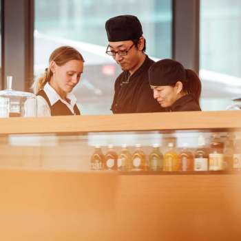 Three employees of the café in the Liechtenstein Art Museum, working together at the counter and exchanging ideas.