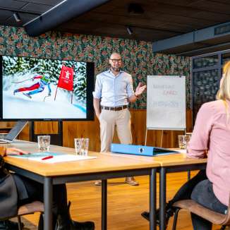 Modern conference room with participants in a business meeting, presentation about skiing in Liechtenstein on the screen