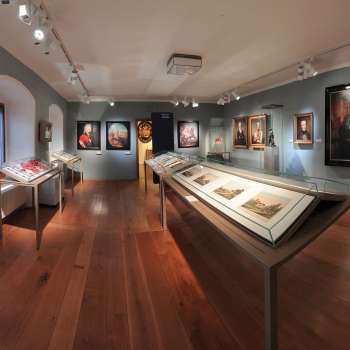 Panoramic view into an exhibition room of the NationalMuseum with historical paintings and showcases.