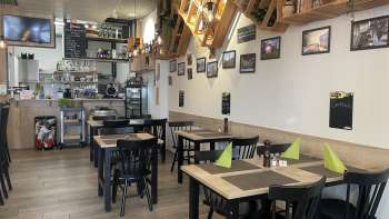 Cozy restaurant interior with modern wooden tables, green napkins and decorative elements