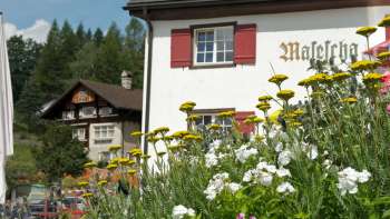 Traditional mountain inn with red shutters and blooming flowers in the foreground