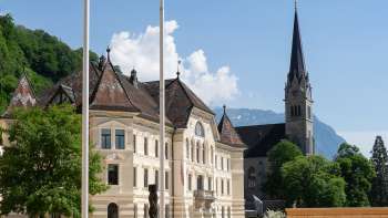  View through a round arch of the government district in Vaduz with the parliament building and St. Florin's Cathedral.