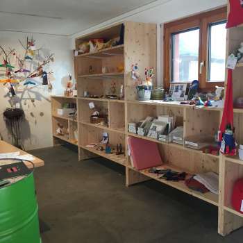 Interior of the Birkahoflädile with wooden shelves full of regional products, decoratively designed with colorful elements - farm store in Liechtenstein.