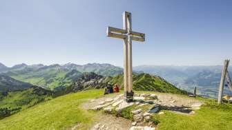 Summit cross on Schönberg mountain with mountains and view of the Rhine valley in the background