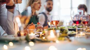 Atmospheric dinner party: people sit together at a festively set table and enjoy a dinner