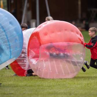 Kids play bubble soccer outdoors - fun and action on an outdoor adventure in Liechtenstein
