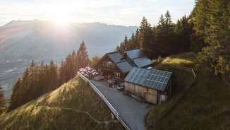 Panoramic shot of a remote mountain hut in Liechtenstein with a view of the Rhine Valley and solar technology on the roof