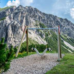 Hanging swing on the Swing Trail Malbun with a view of steep rock faces and alpine landscape in Liechtenstein