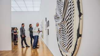Visitors view modern works of art in a gallery of the Liechtenstein Art Museum with bright architecture and wooden flooring