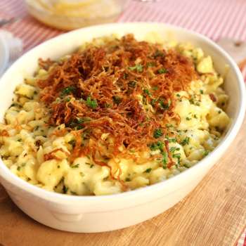Traditional Käsknöpfle with fried onions - served in a plate on a wooden board