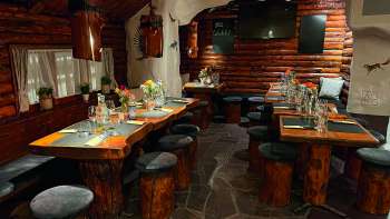 View of a rustic restaurant with wooden furniture, green decorated tables and candles