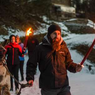 Group on a guided llama hike in snowy Liechtenstein with torches - atmospheric outdoor adventure for young and old.