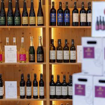 Interior of the Court Winery with stylishly illuminated wooden shelves full of wine bottles and cartons.