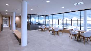 Bright seating area in the Triesen indoor pool with a view of the pool through the glass front.