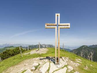 Summit cross on Schönberg mountain with mountains and view of the Rhine valley in the background