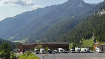 Several motorhomes are parked on the sunny pitch in Malbun with a mountain panorama in the background