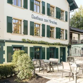 Inviting terrace with wooden tables and chairs in front of the Gasthaus zum Hirschen
