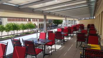 Sunny terrace with red chairs and tables set in white