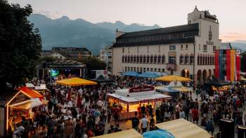 The Vaduz Town Hall at dusk with fairy lights, children playing on a table tennis table and a summery atmosphere on the national holiday