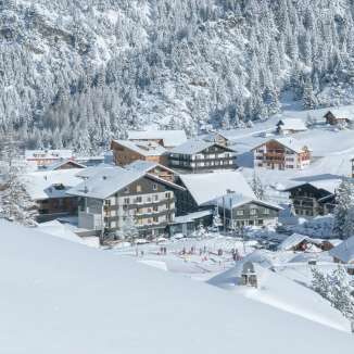 Snow-covered winter landscape in the Liechtenstein ski resort of Malbun with a view of the village and surrounding mountain slopes.