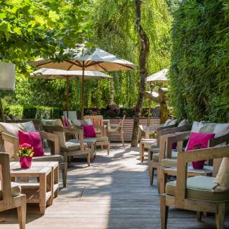Comfortable seating area with cushions, plants and parasols on the terrace of the Park Hotel Sonnenhof in Vaduz, Liechtenstein