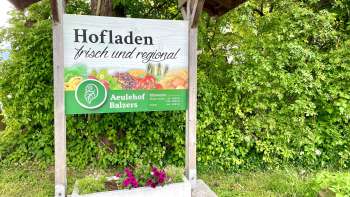 Aeulehof farm store sign with the words "Fresh and regional" in front of a green hedge in Triesen.