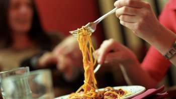 Person picks up spaghetti with a fork from a plate at Brasserie Burg