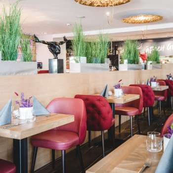 : Generously laid tables in the PUR Restaurant & Bar with red chairs and floral table decorations.