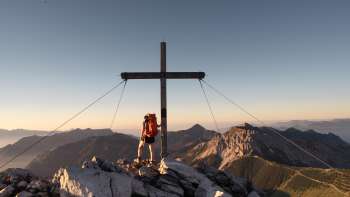 Hiker at the summit cross on Augstenberg mountain