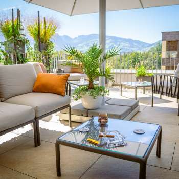 Terrace seating area with cocktails and views of the Liechtenstein Alps