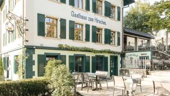 Inviting terrace with wooden tables and chairs in front of the Gasthaus zum Hirschen