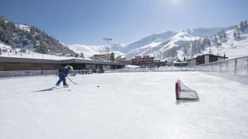 Spacious ice rink in Malbun against an impressive mountain backdrop in glorious sunshine