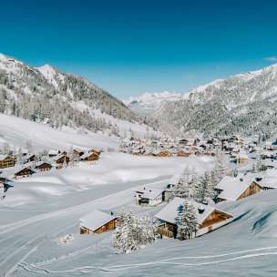 Aerial view of Malbun in winter with snow-covered wooden houses, nestled in the Liechtenstein Alpine landscape