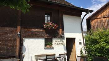 Rustic inn with wooden façade and flower-decorated windows, surrounded by green nature