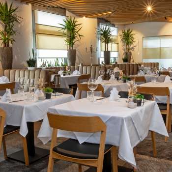 View of the stylishly furnished Alpspitz restaurant with white-clothed tables and a modern, bright atmosphere.