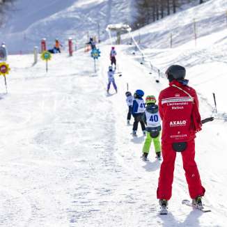 Ski instructor accompanies children on the practice lift in Malbun - ideal ski area for families and beginners in Liechtenstein.