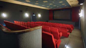 Side view of the cinema auditorium of the Altes Kino Vaduz with red armchairs and atmospheric lighting.