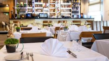  Tastefully laid table in the Alpspitz restaurant with a view of the bar in the background.