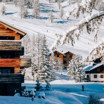 Cozy chalets in the winter sports resort of Malbun surrounded by snow-covered trees and ski slopes in the background