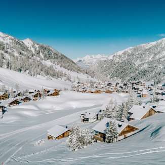 Aerial view of Malbun in winter with snow-covered wooden houses, nestled in the Liechtenstein Alpine landscape